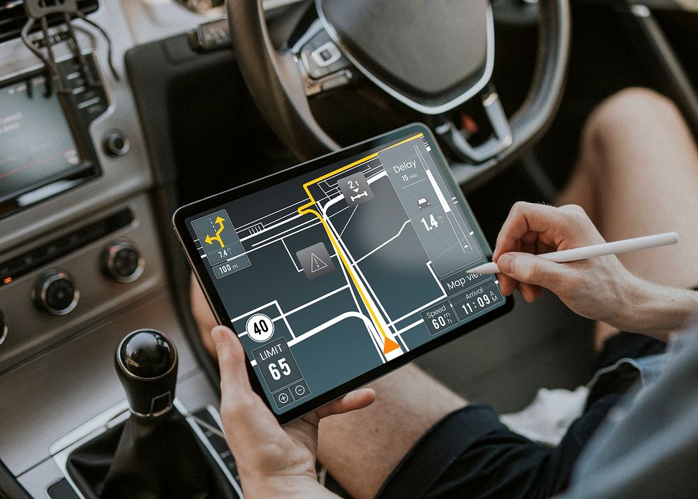Hand holding stylus pen using map on a tablet in a car