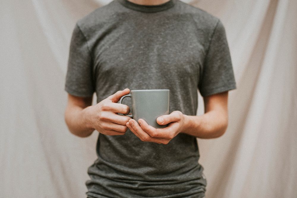 Man holding a gray ceramic coffee cup