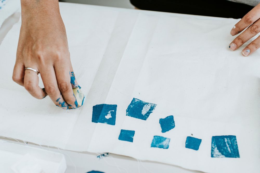 Artist hand stamping paint on fabric 