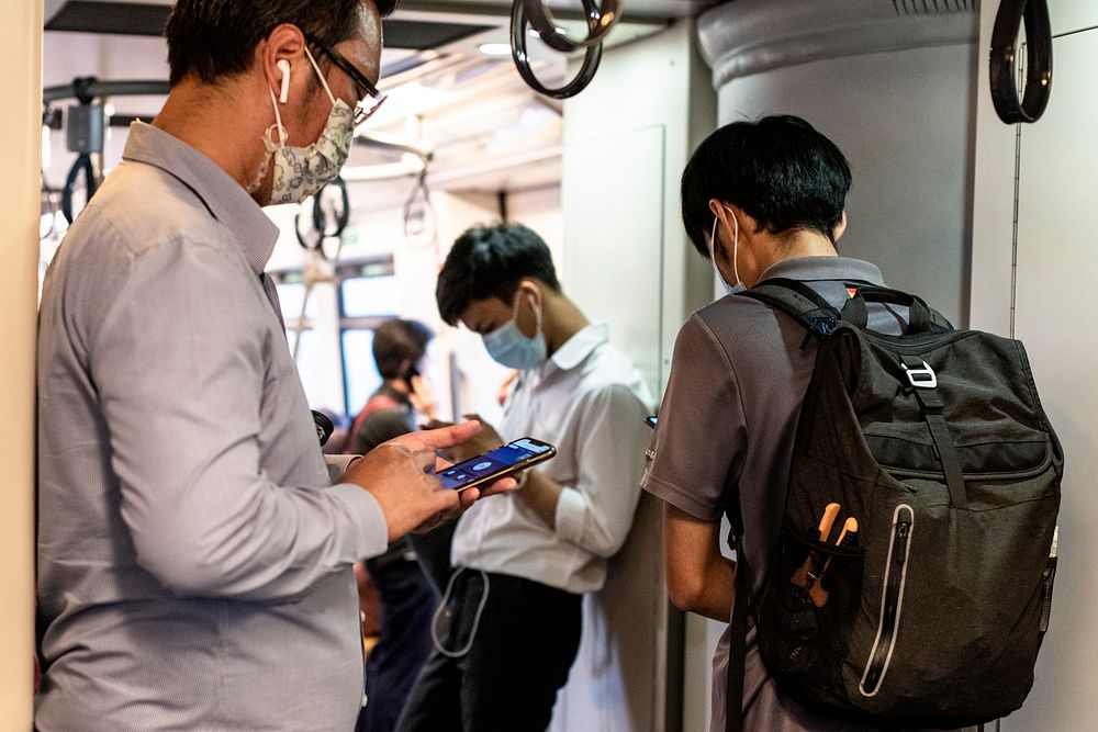 People using phones on Bangkok BTS Skytrain. BANGKOK, THAILAND, 16 APRIL 2021