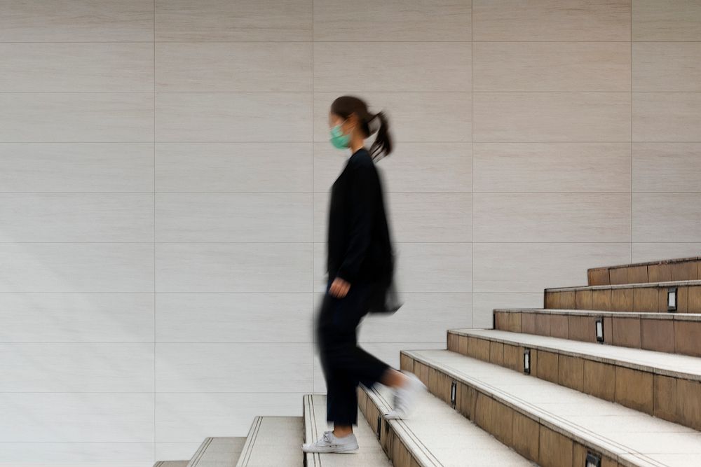 Woman in a mask walking down the stairs