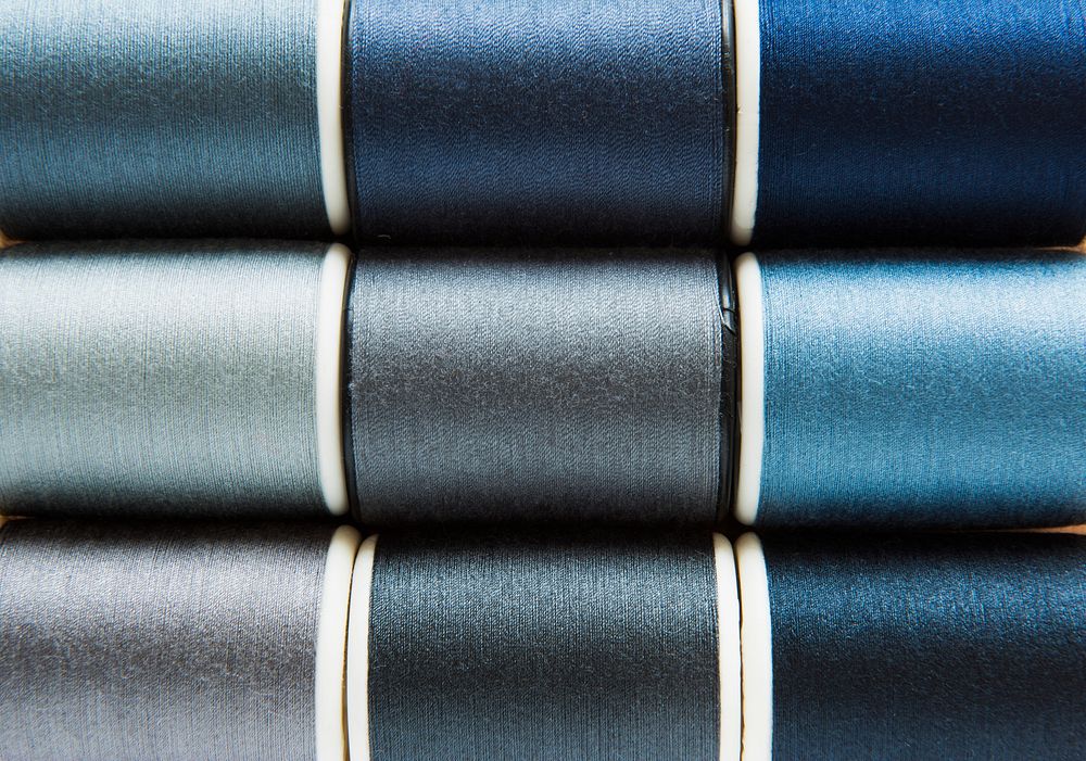 Shades of gray and blue sewing threads background closeup