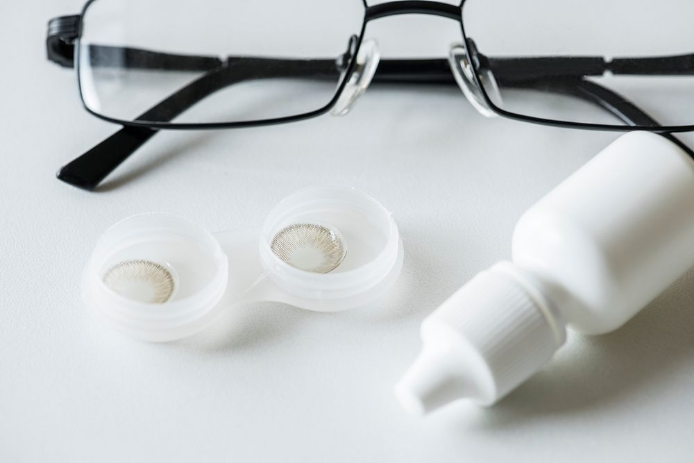 Closeup of contact lens, bottle of solution and an eyeglasses optometry concept