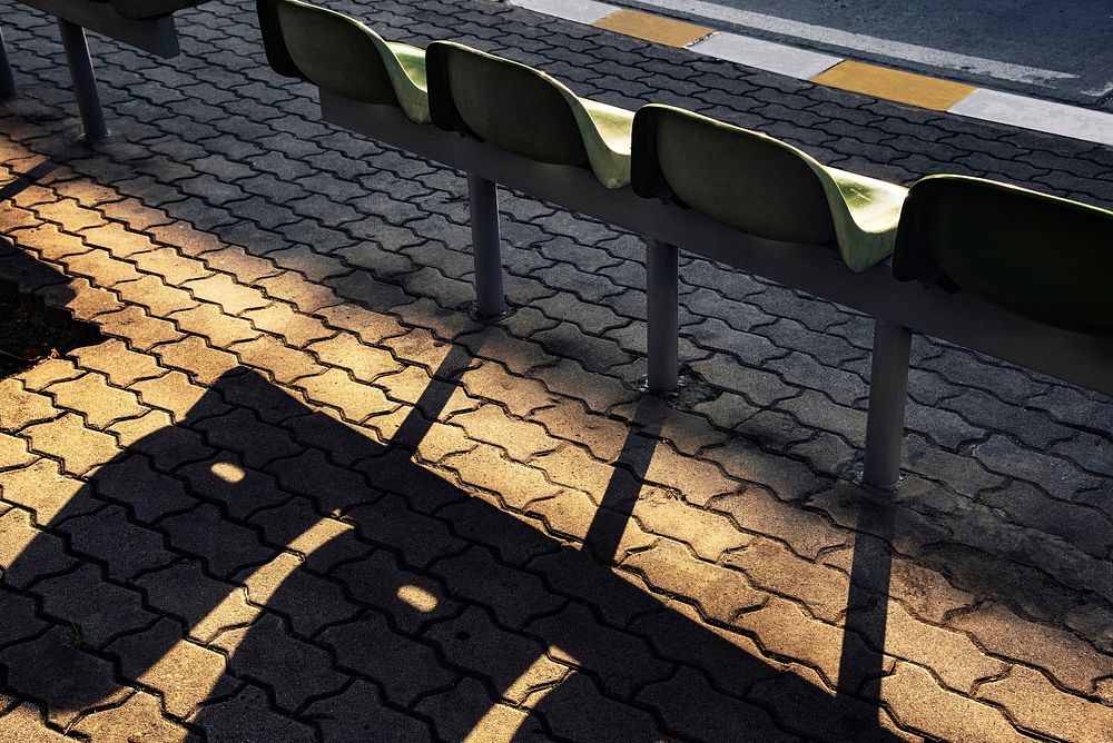 Bus stop with plastic seats casting shadow