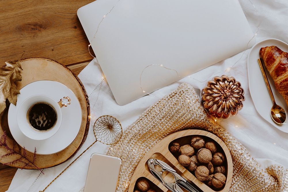 Walnuts in a wooden box served with a cup of coffee next to a laptop
