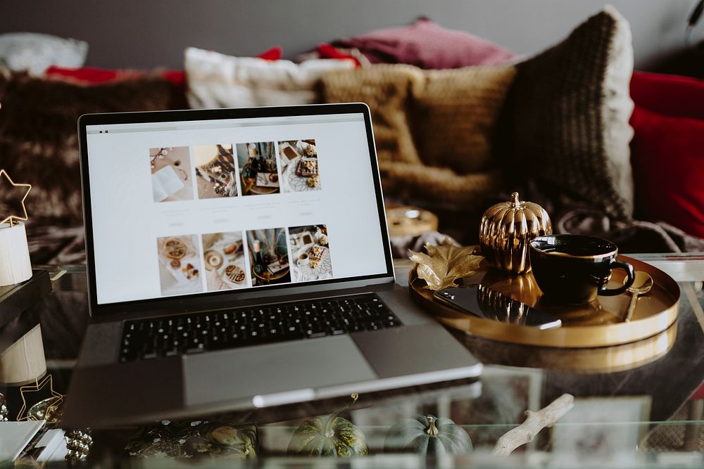 Laptop on a glass table showing a photo feed