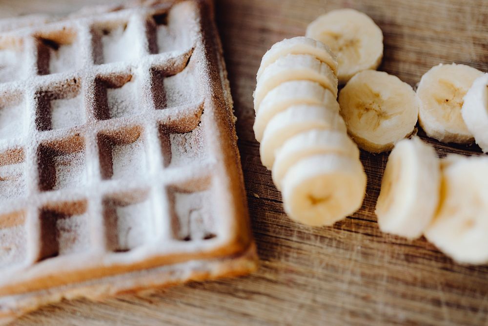 Waffle and slices of banana on a wooden tray