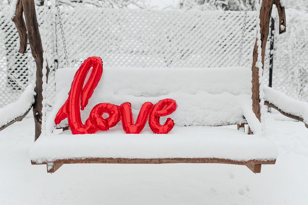 Red love balloon word on a snowy swing
