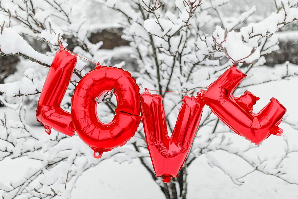 Red love balloon word hanging on a snowy tree