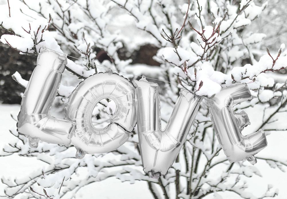 Silver love balloon word hanging on a snowy tree