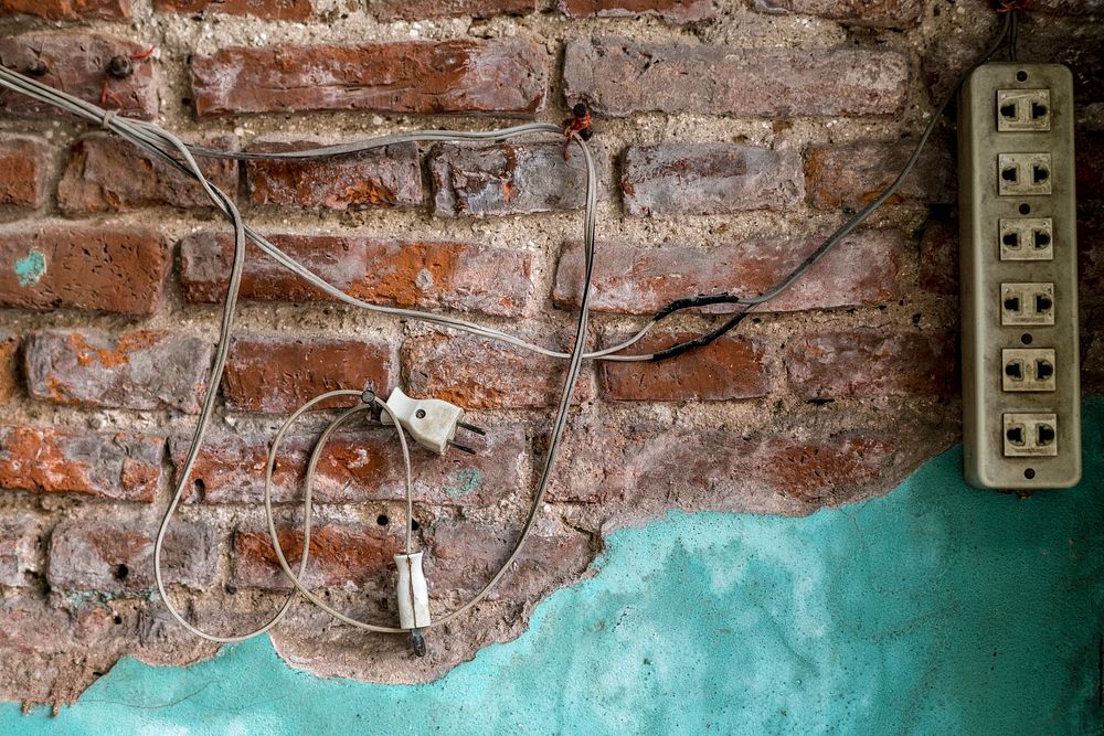Power plug hanging on a brick wall