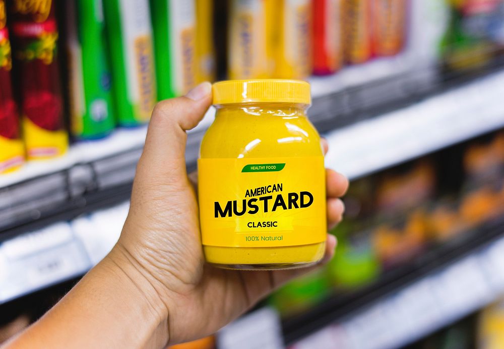 Hand holding a mustard jar in a grocery store