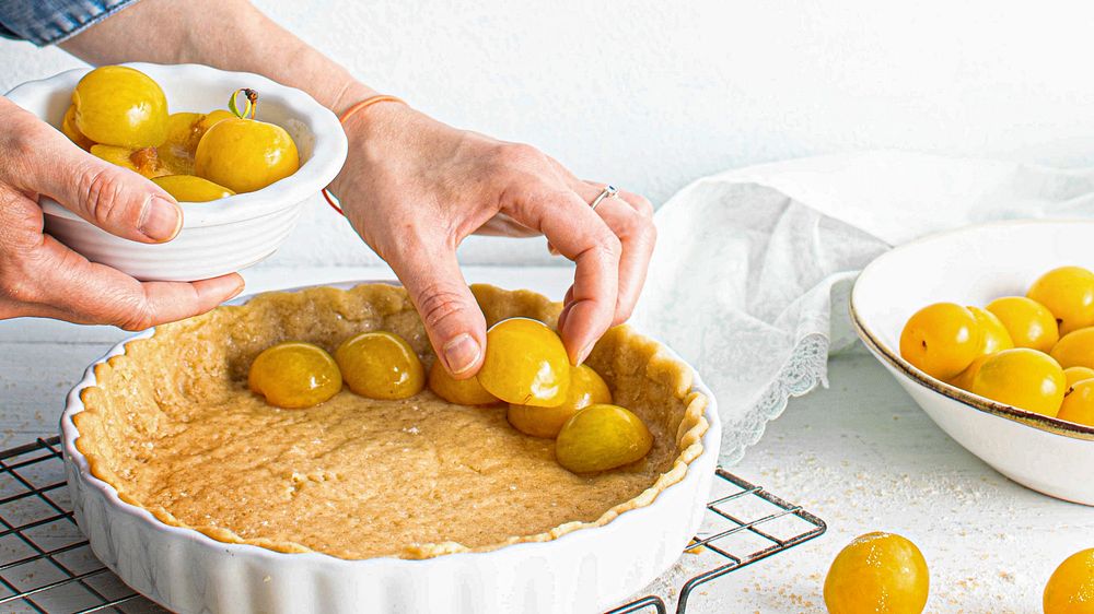 Woman filling pie crust with mirabelle plums