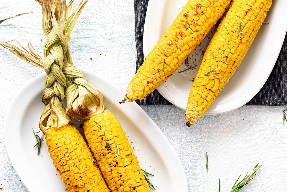 Fresh corn on the cob with organic rosemary leaves