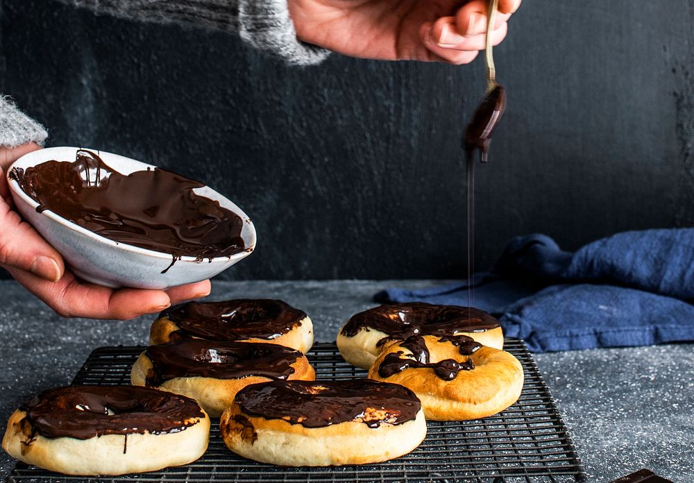 Patissier coating homemade donuts with chocolate sauce
