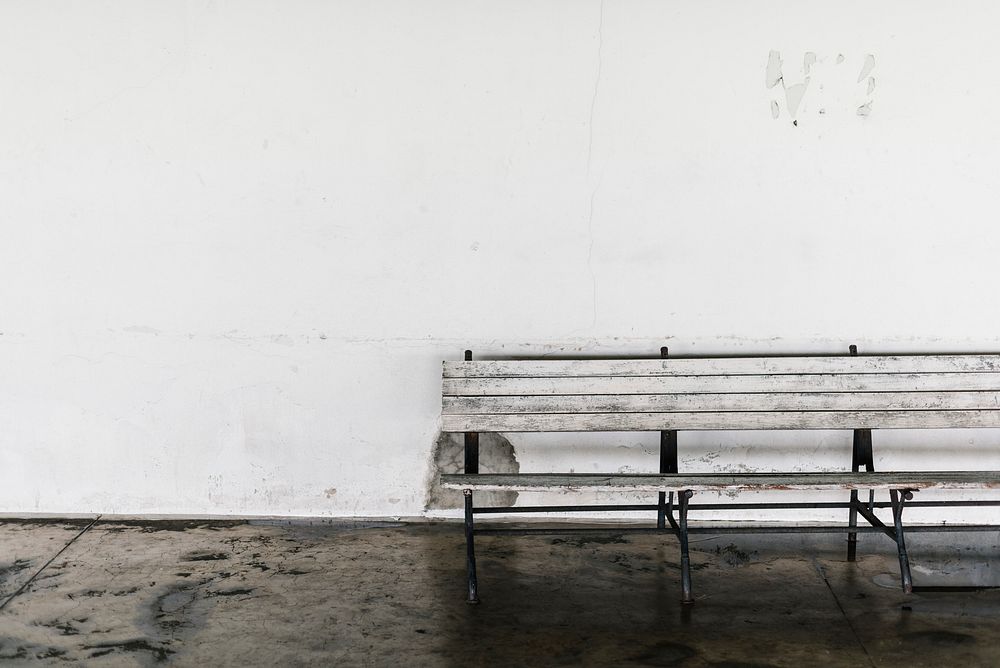 Grungy bench against a white wall