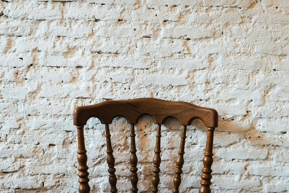 Wooden chair against white brick wall