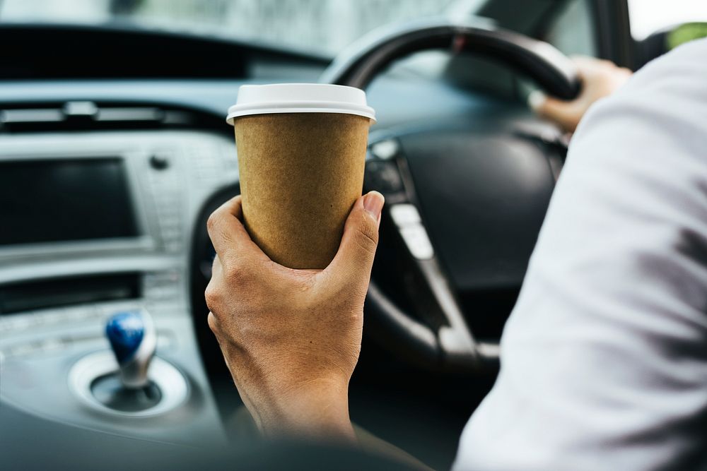 Holding takeaway coffee cup in a car