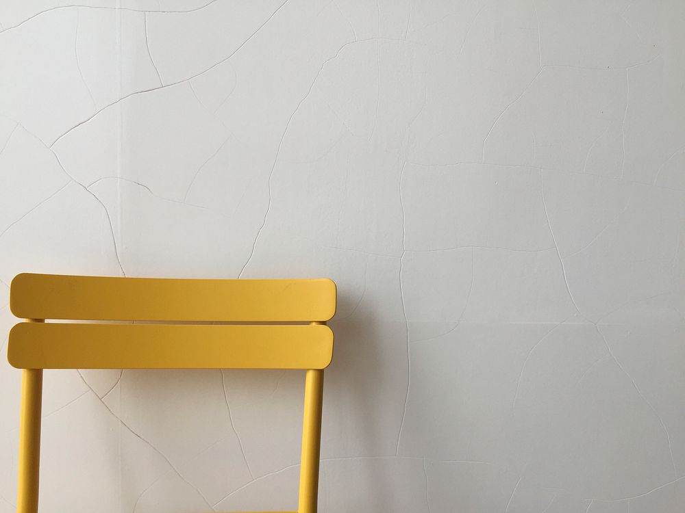 Yellow chair against a cracked wall