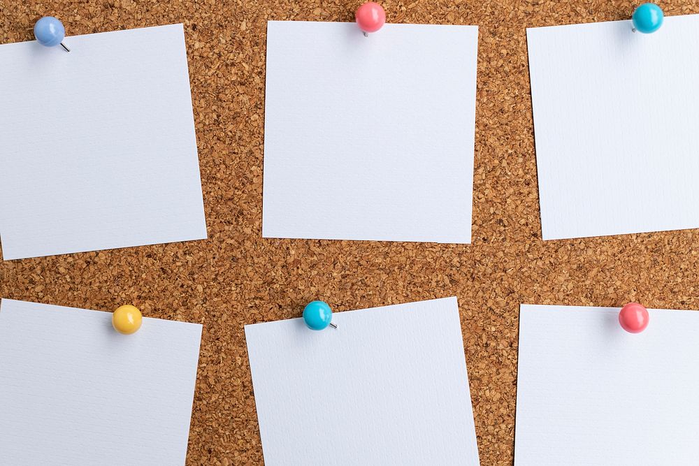 Blank white note papers pinned on brown corkboard