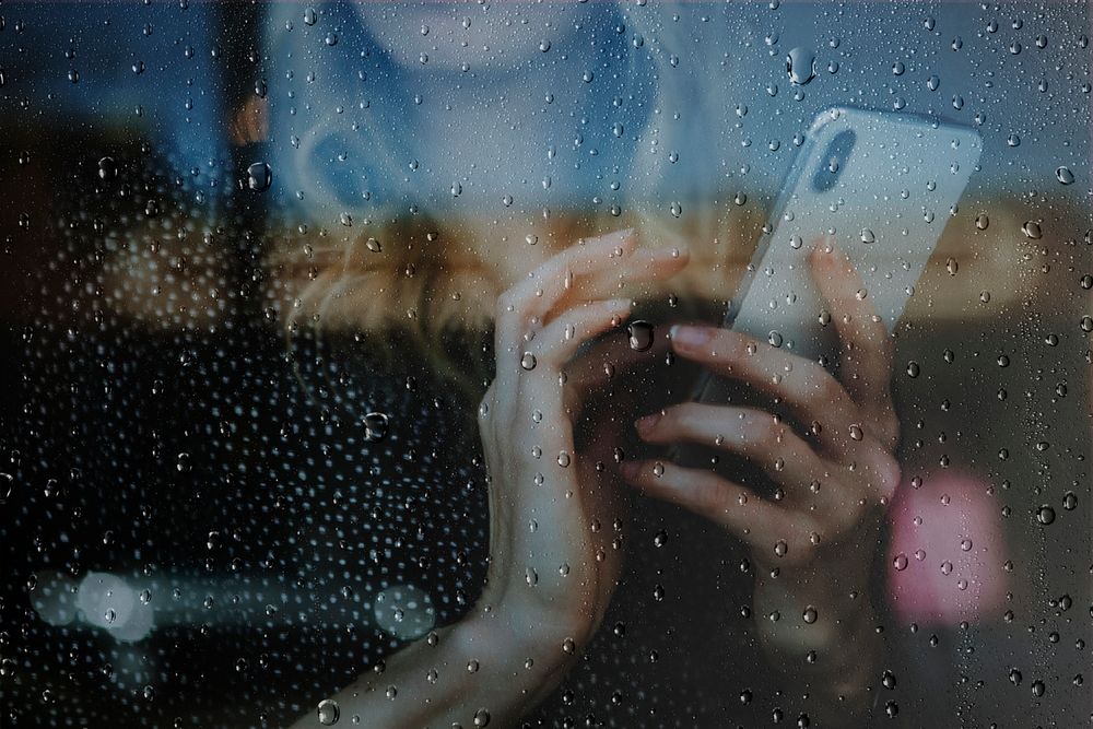 Rainy window background, woman using a phone