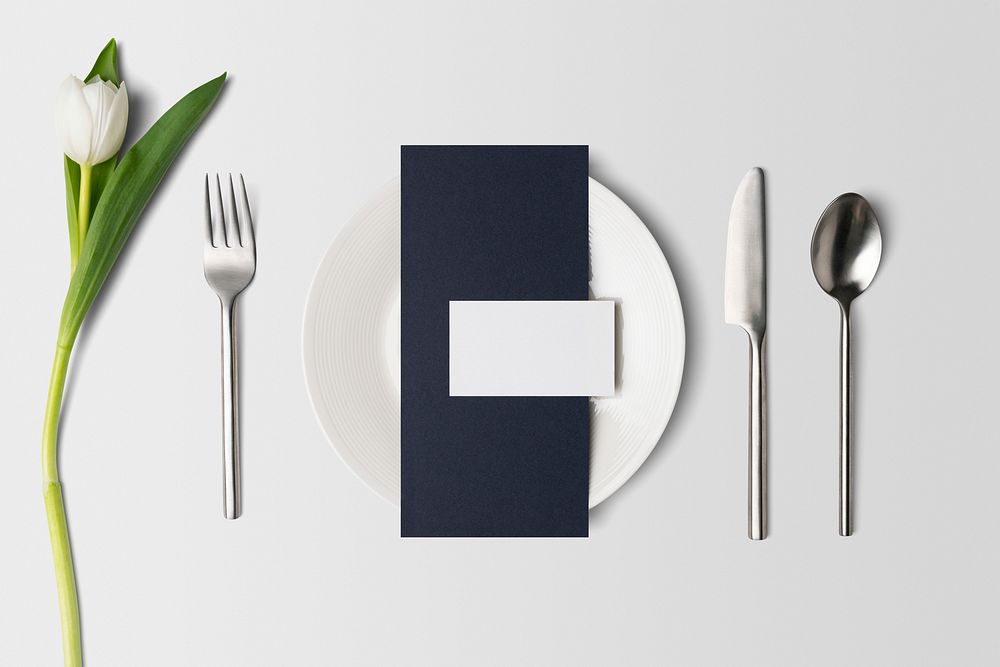 Blue menu card on white plate, table setting flat lay