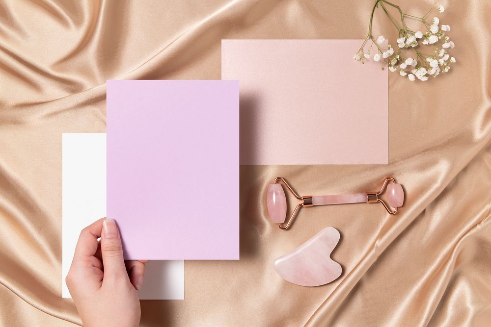 Blank pink papers with jade roller and gua sha, flay lay