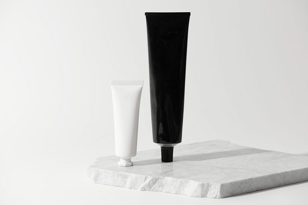Black and white tubes, beauty product packaging, on marble product stand
