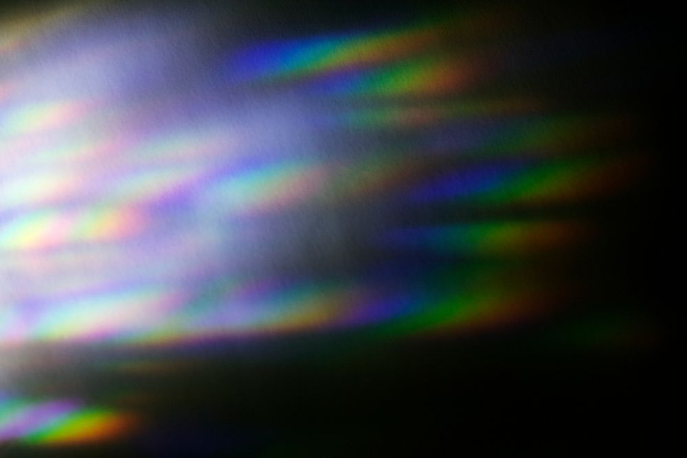 Iridescent rainbow prism light flare on black background
