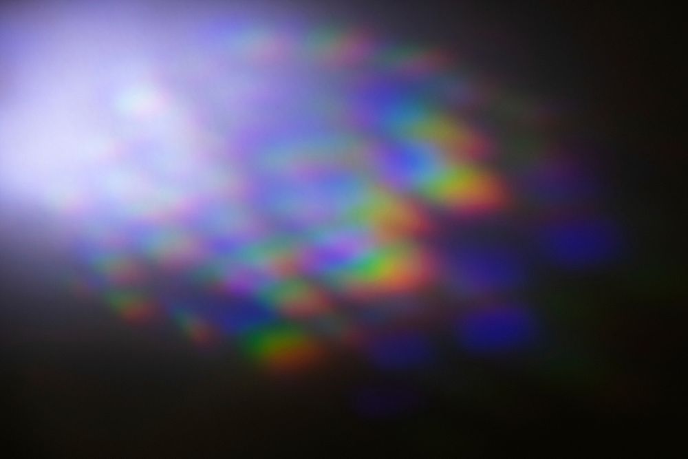 Neon lens flare prism rainbow light reflection on black background 