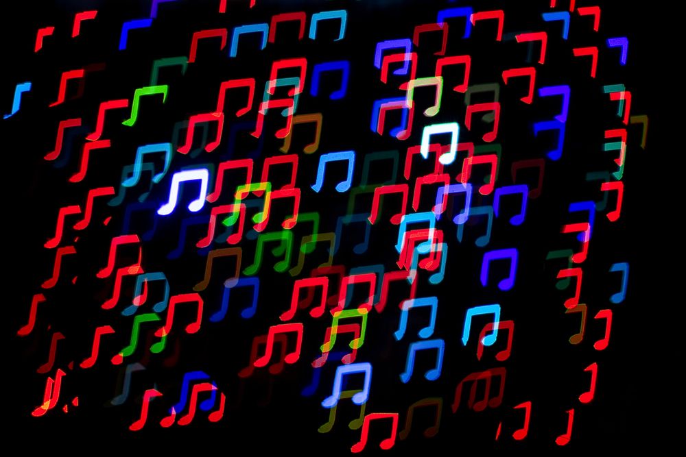 Colorful glitter beam musical note sequin confetti on black background