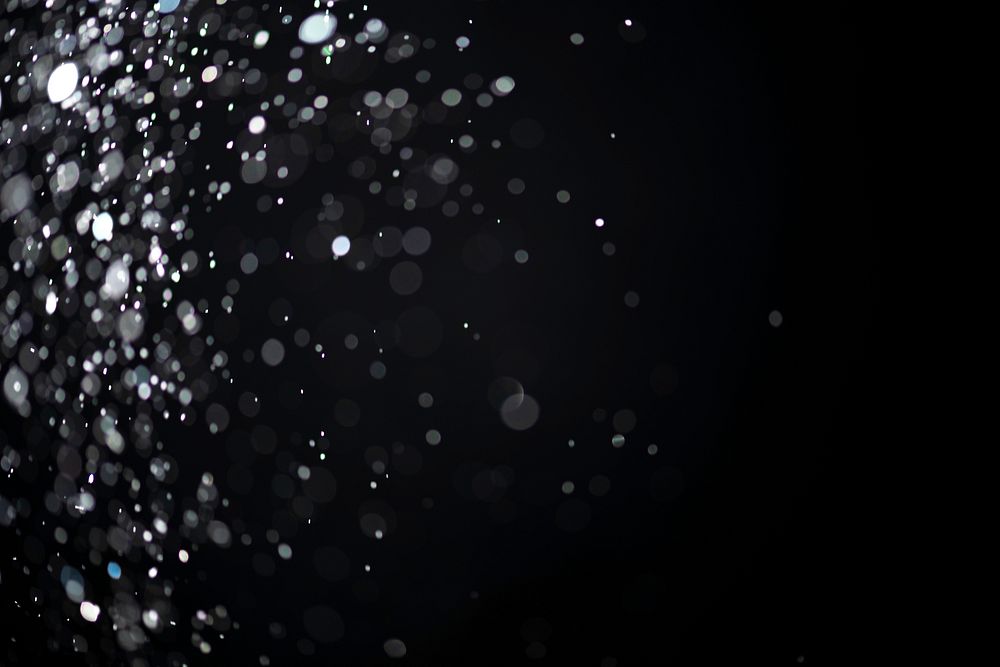 White falling glitter sequin confetti on dark black background