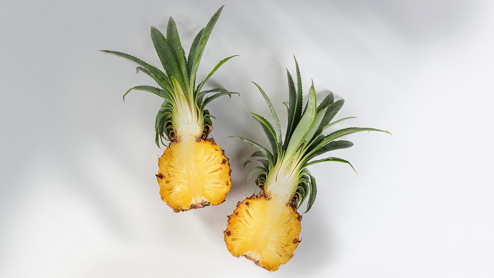 Fresh pineapple cut in half on off white background