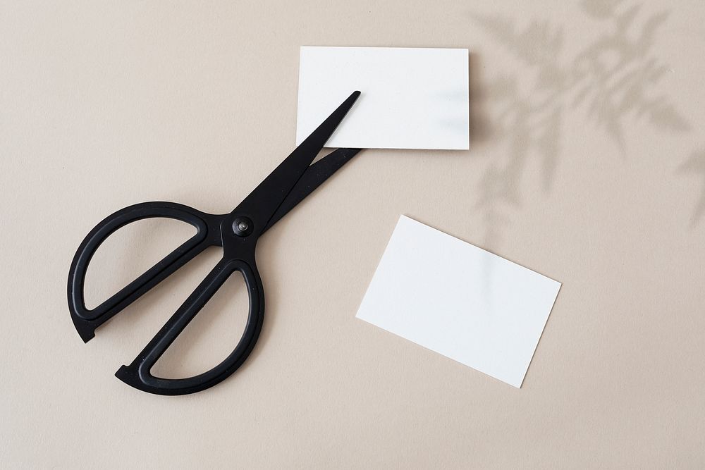 White business cards with scissors on a concrete wall
