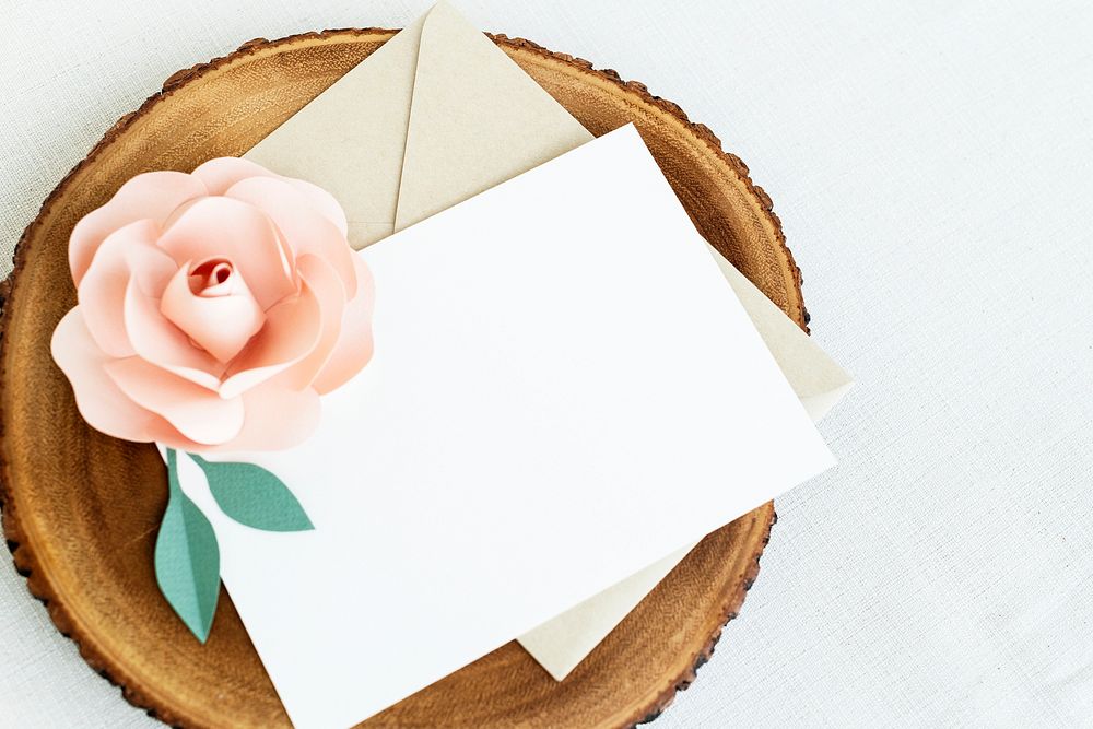 Blank white card on a wooden plate with a pink rose