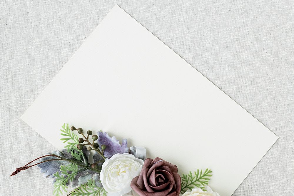 Blank white card with flowers on white fabric textured background