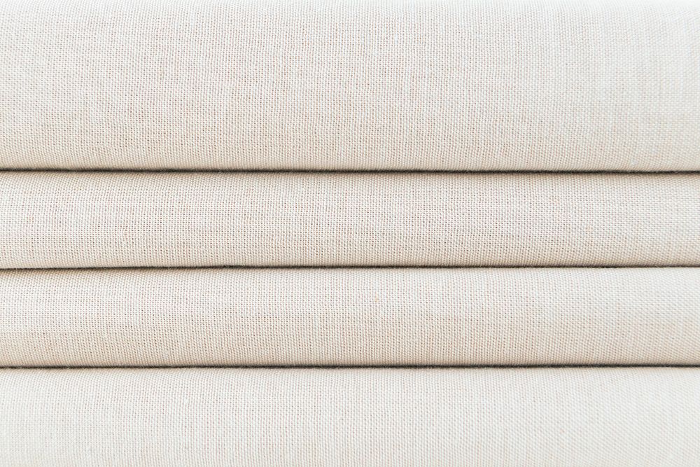 Stack of folded beige woven fabric patterned background