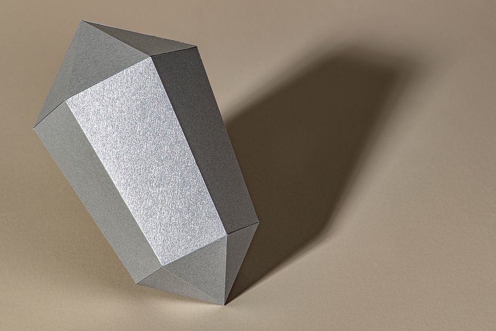 Silver hexagonal prism paper craft on a beige background