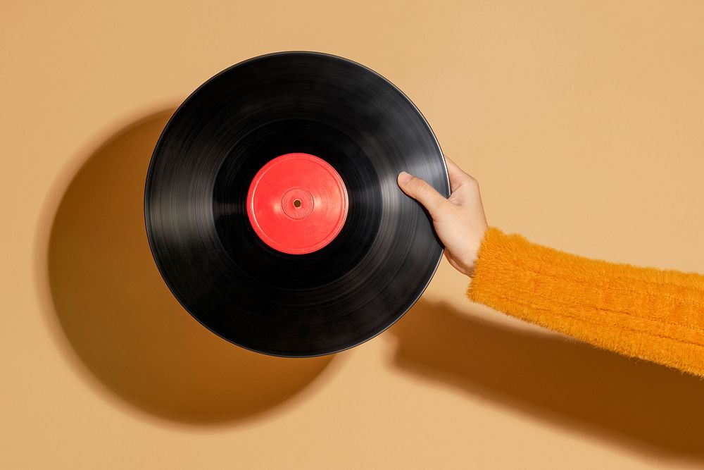 Woman holding a vinyl record on a beige background 