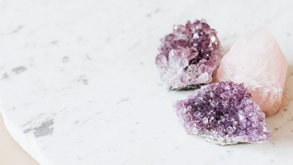 Amethyst and rose quartz crystals on a marble countertop 