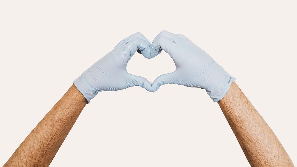 Gloved hands making a heart shaped sign on a beige background