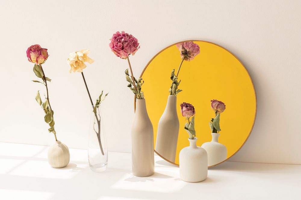 Dried flowers in minimal vases by a round mirror