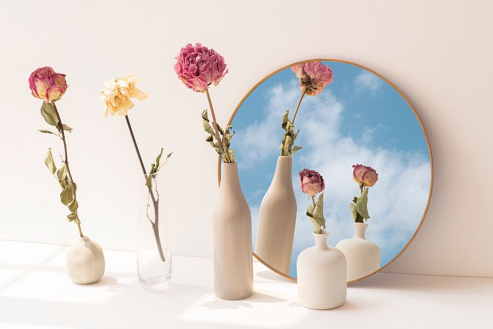 Dried flowers in minimal vases by a round mirror
