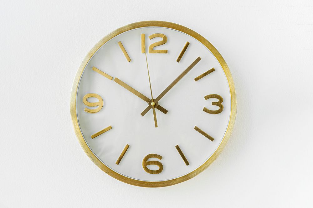 Round gold analog clock hanging on a wall