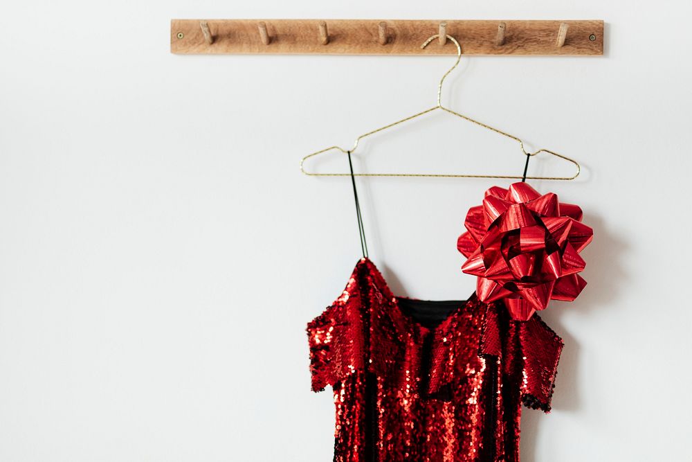 Red off shoulder sequin dress with a bow on a wall hanger