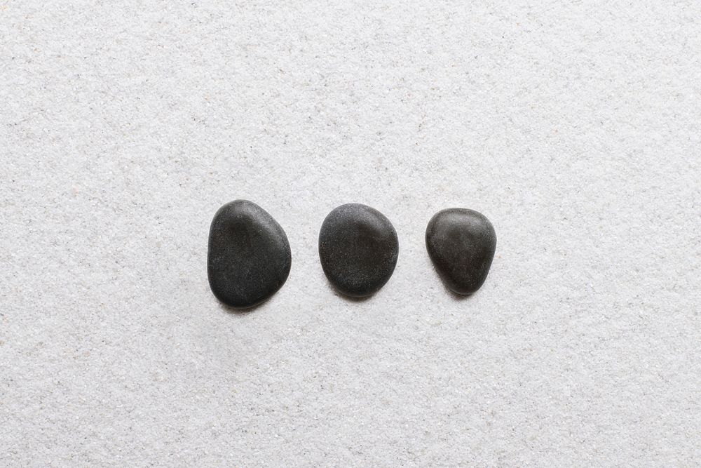 Black zen stones stacked on white background in wellness concept