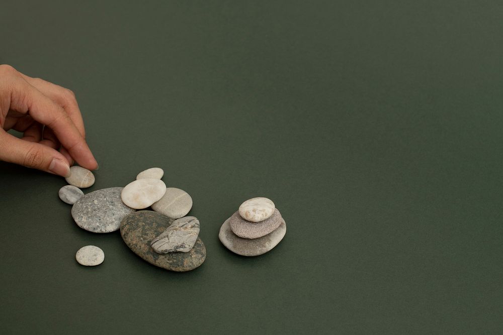 Hand stacking zen stones on the sand wellness background