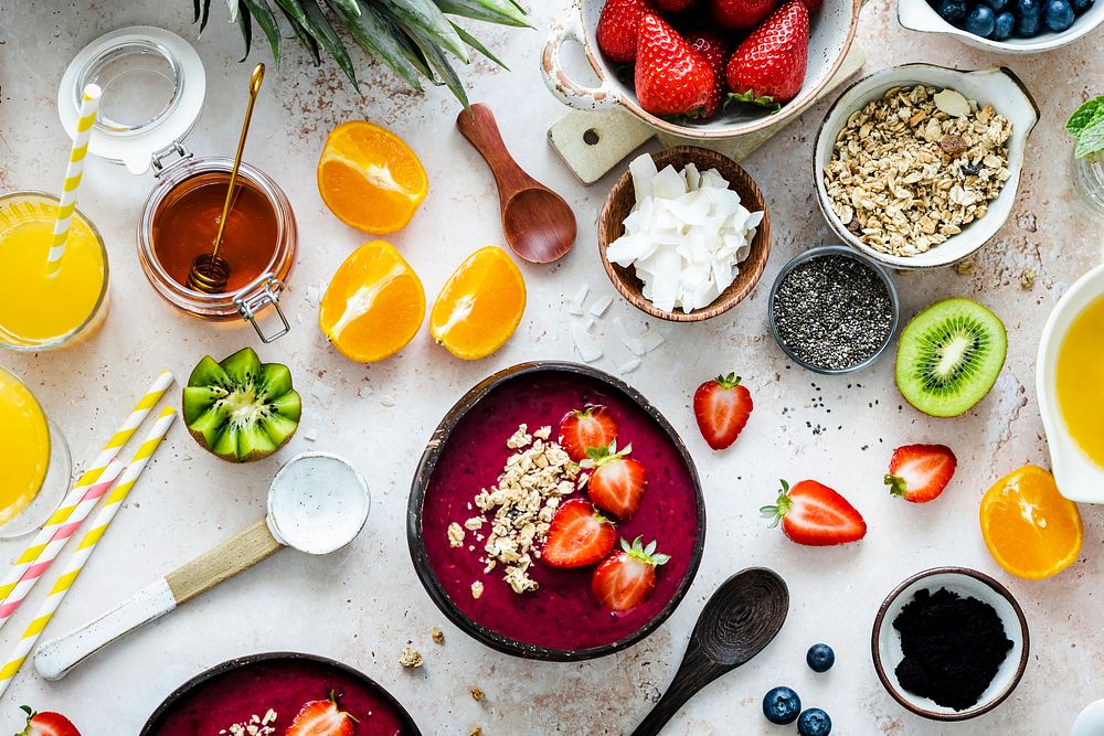 Preparing acai bowl in flat lay style with tropical fruits and grains