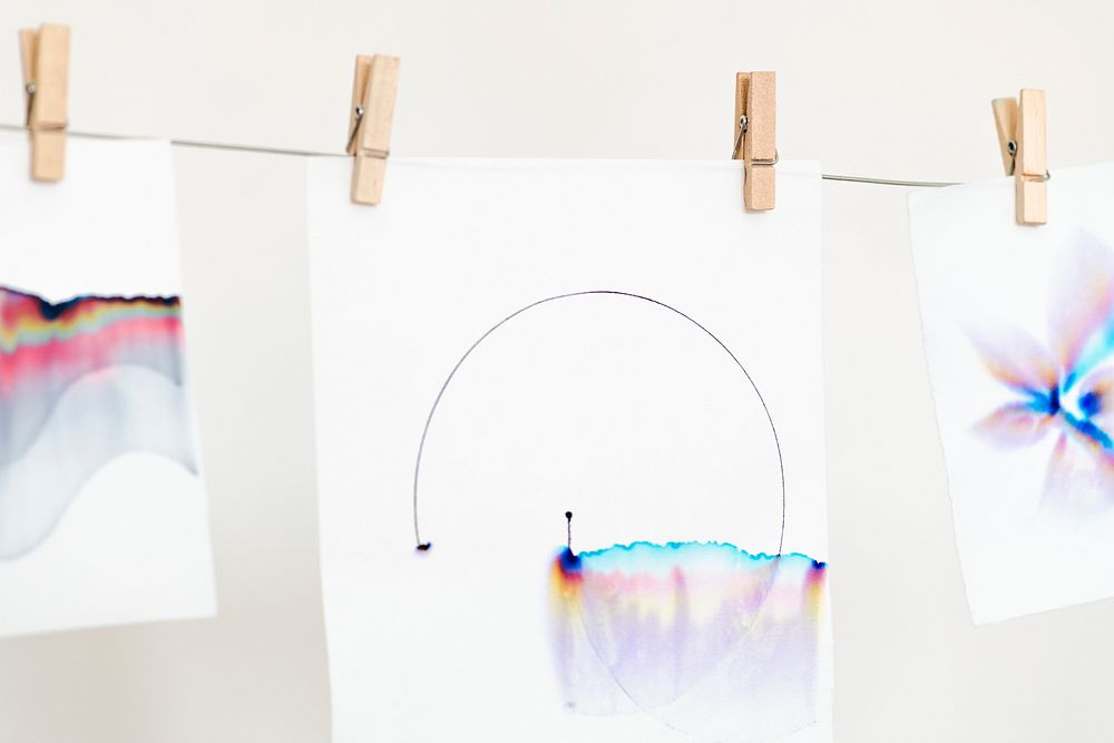 Aesthetic chromatography art on white papers hanging on a rope