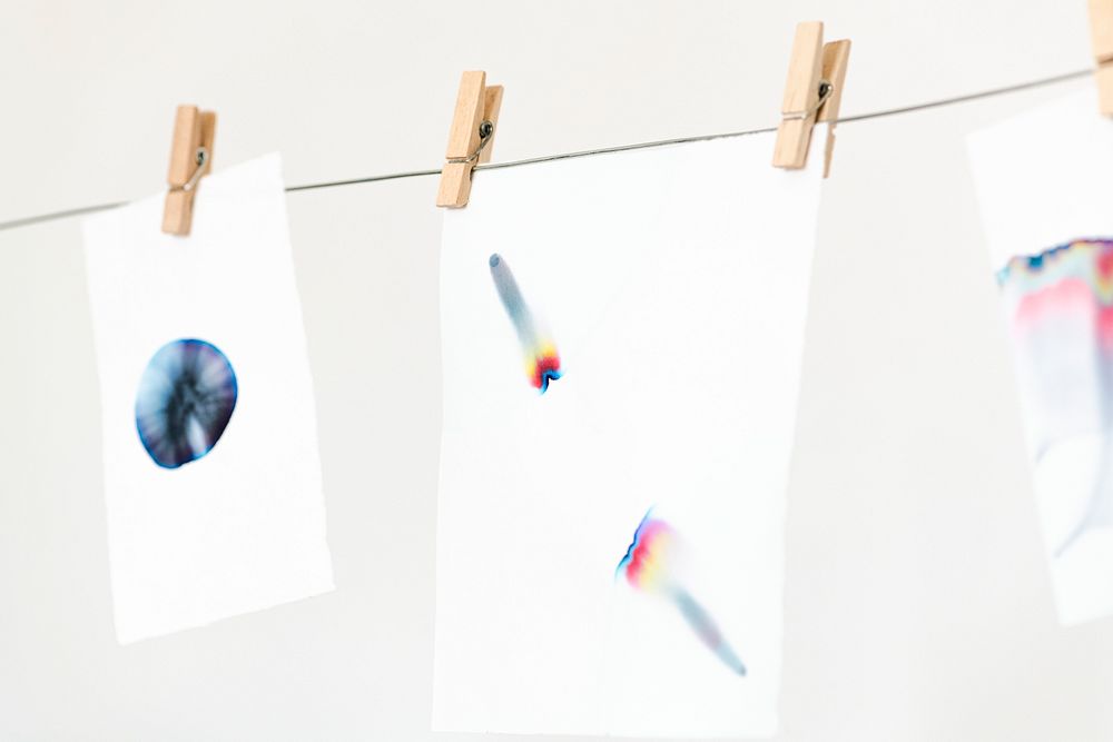 Aesthetic chromatography art on white papers hanging on a rope